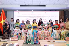 Delegates and children take part in an ao dai fashion show. (Photo: VNA)