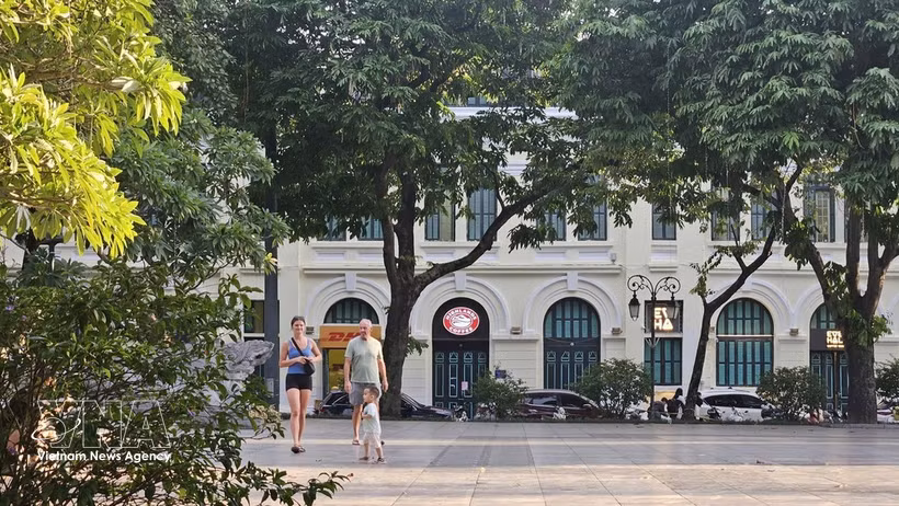 International visitors stroll beneath the leafy trees along Hoan Kiem Lake, enjoying Hanoi’s cool autumn weather. (Photo: VNA)
