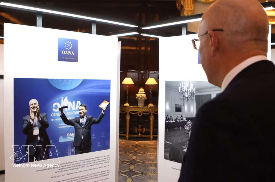 A delegate admires a photograph capturing the moment VNA Director General Nguyen Duc Loi receives the OANA Award for Excellence in News Agency Quality from Aslan Aslanov, OANA President for the 2016-2019 term. (Photo: VNA)