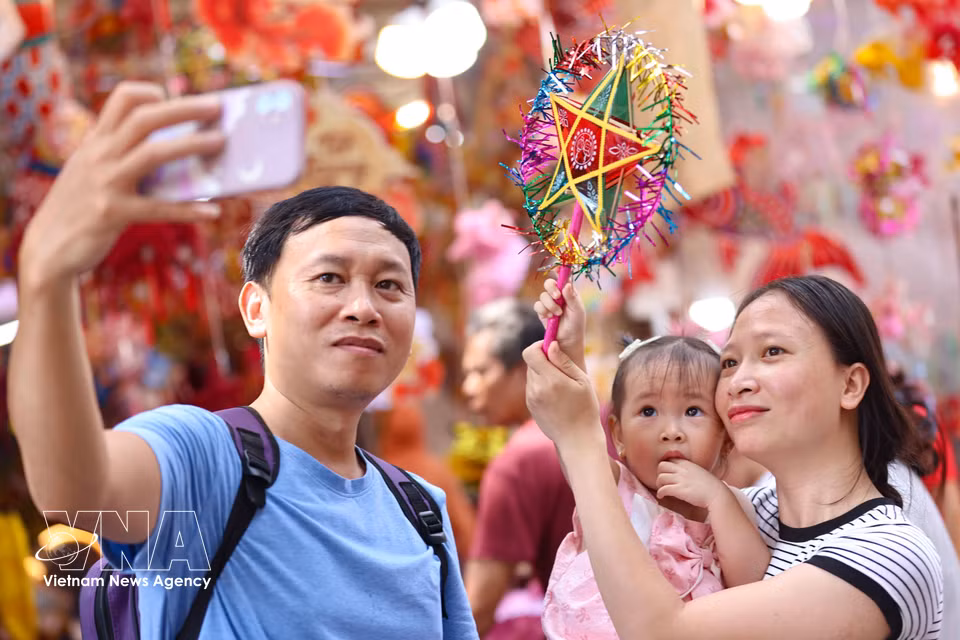 A family captures a memorable moment amid the vibrant colours of the traditional Mid-Autumn market. (Photo: VNA)