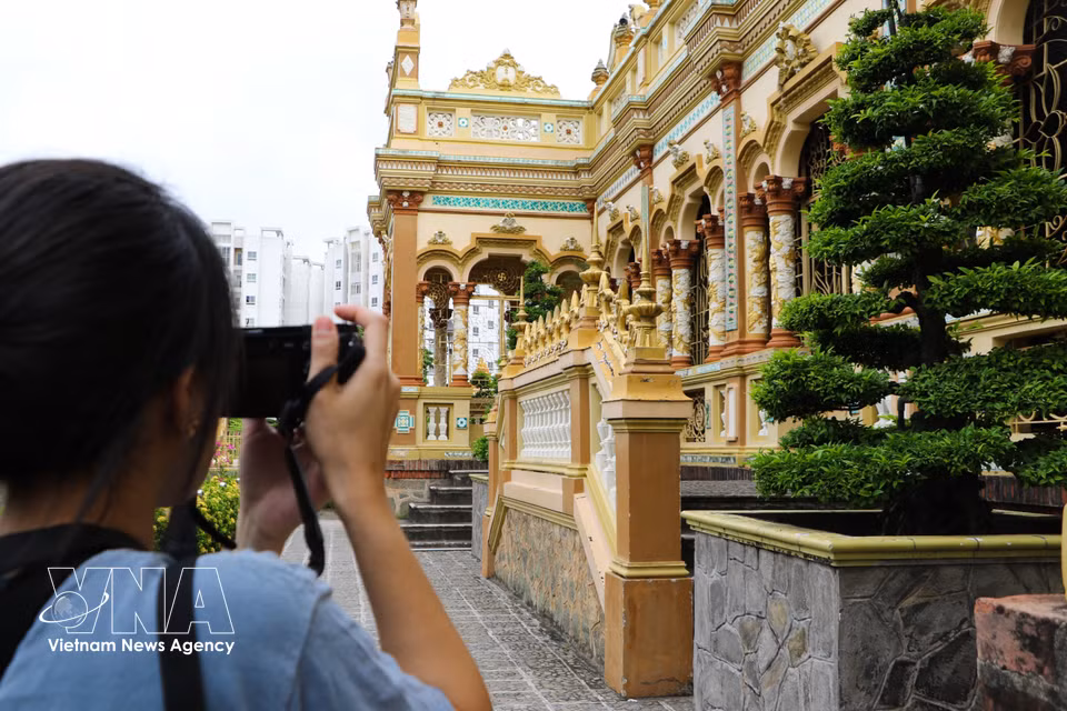 Visitors take photos at Vinh Trang Pagoda. (Photo: VNA)