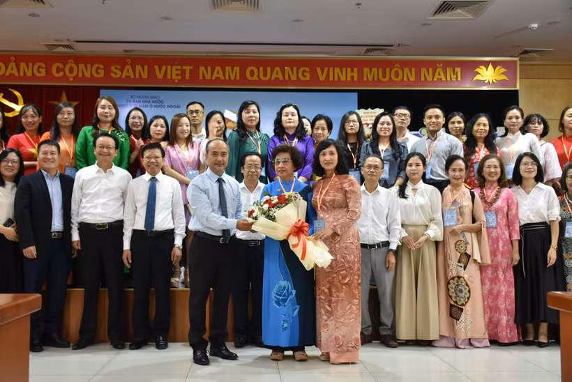 Chairman of the State Committee for Overseas Vietnamese (L) presents flowers to representatives of Vietnamese language teachers abroad. (Photo: VNA)