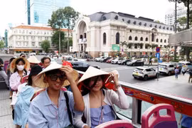 Foreign tourists use conical hats during their tour in Ho Chi Minh City. (Photo: VNA)